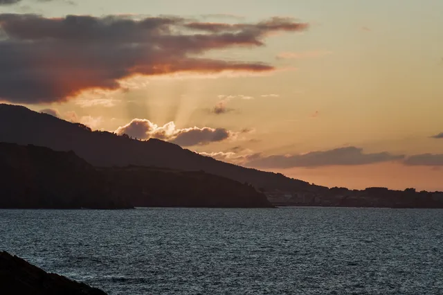 Sun rays breaking through clouds over a bay at dusk