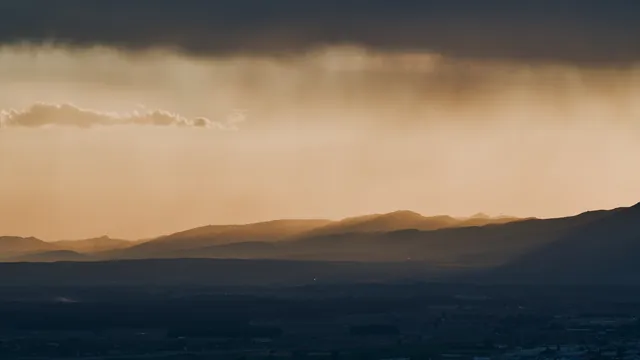 Evening light breaking through clouds over a mountain range